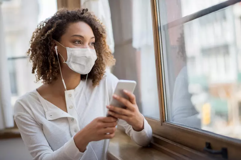 A woman wearing  face mask and using her cell phone. 