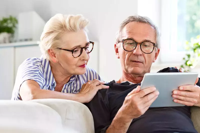 An older couple reading on a tablet.