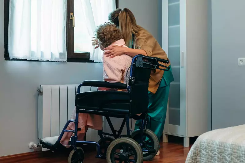 Woman embracing elderly woman in hospice/home care
