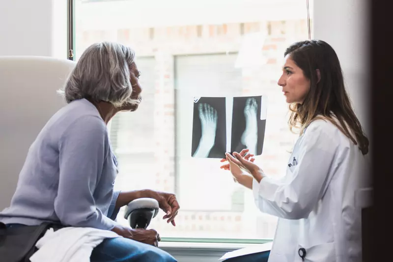 A patient and physician looking at foot x-rays