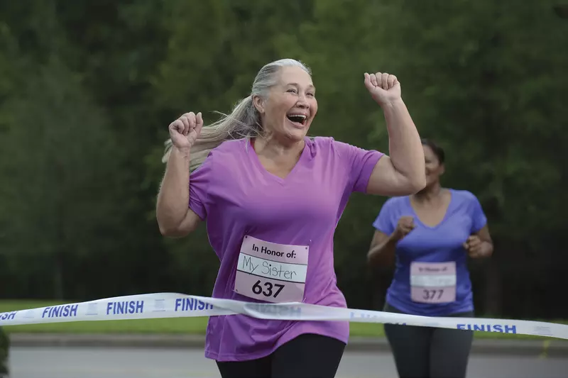 A senior woman crossing the finish line in a race