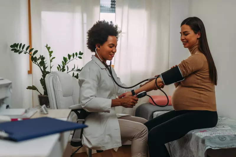 Pregnant woman getting her blood pressure checked by a physician