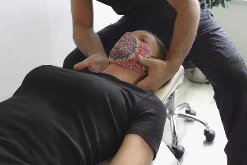 Woman wearing a mask, getting a neck massage