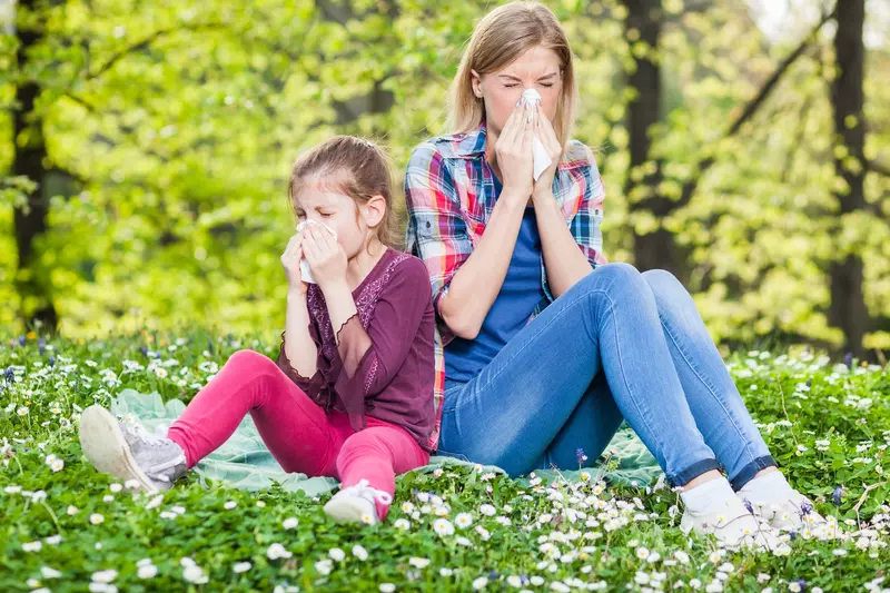 Two ladies experiencing allergy symptoms while sitting outside.