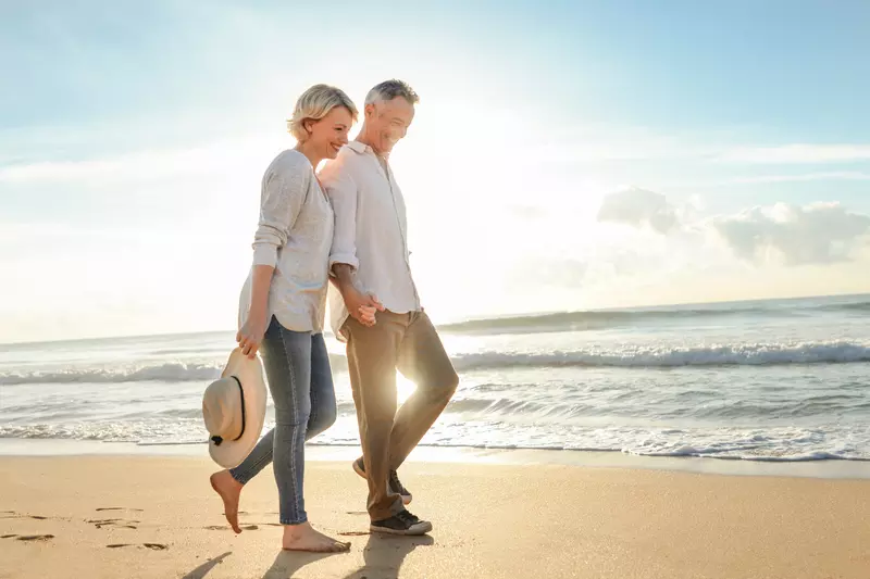 An older couple walks the beach to stay healthy.