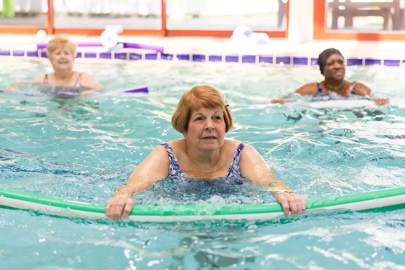 Three senior ladies in the middle of doing a swimming exercise