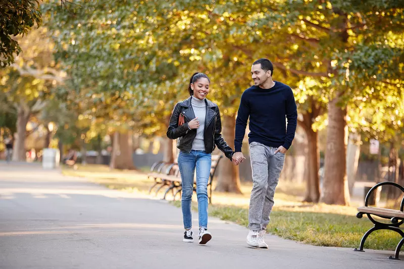 A young couple take a stroll through the park.