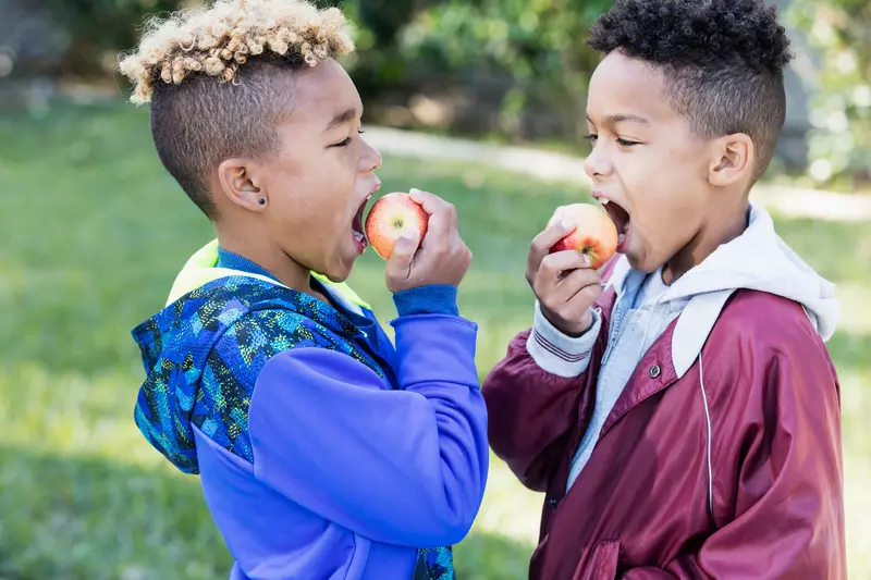 Two boys eating apples.