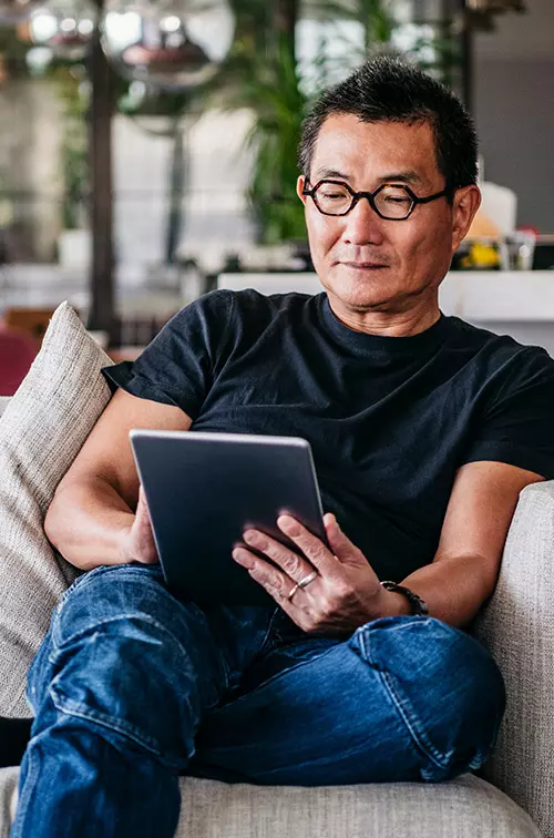 A man reading on his tablet at home.