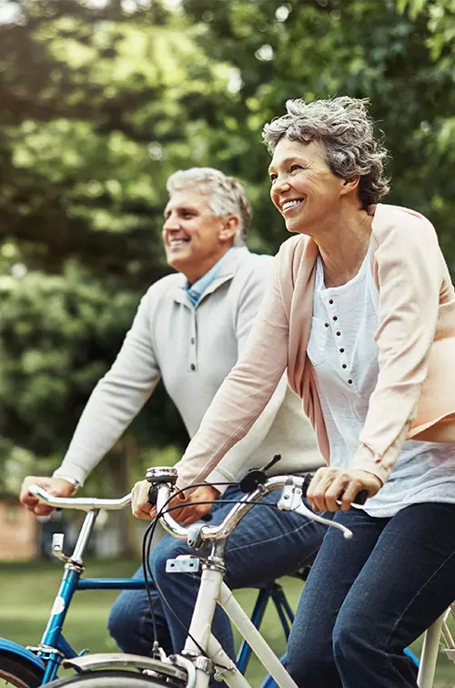 Older couple riding bicycles outdoors.