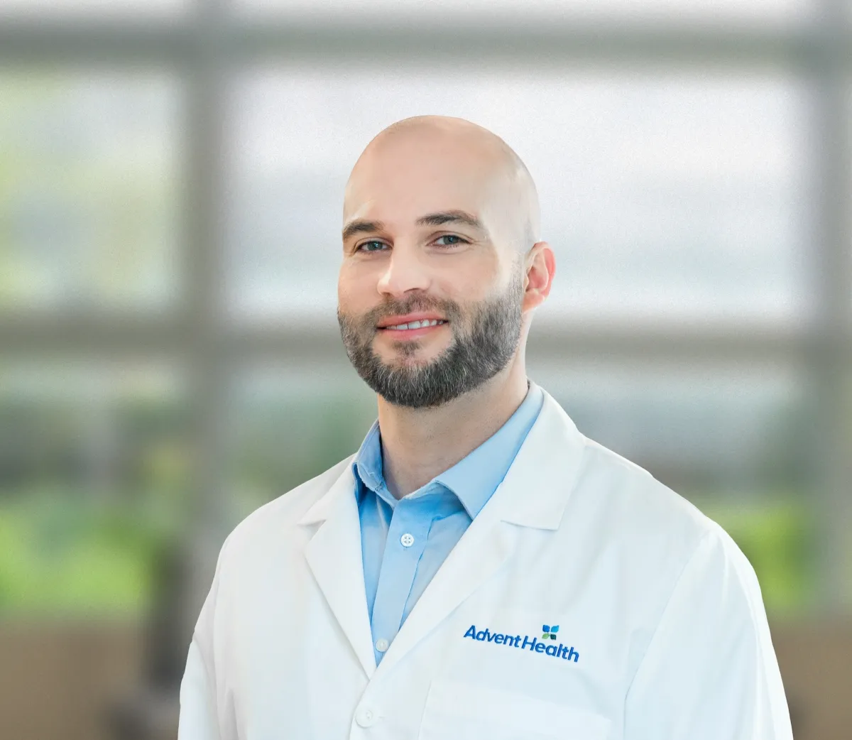 Cody Scoggins, FNPC, a white male in a white coat, stands in front of a blurred lobby background