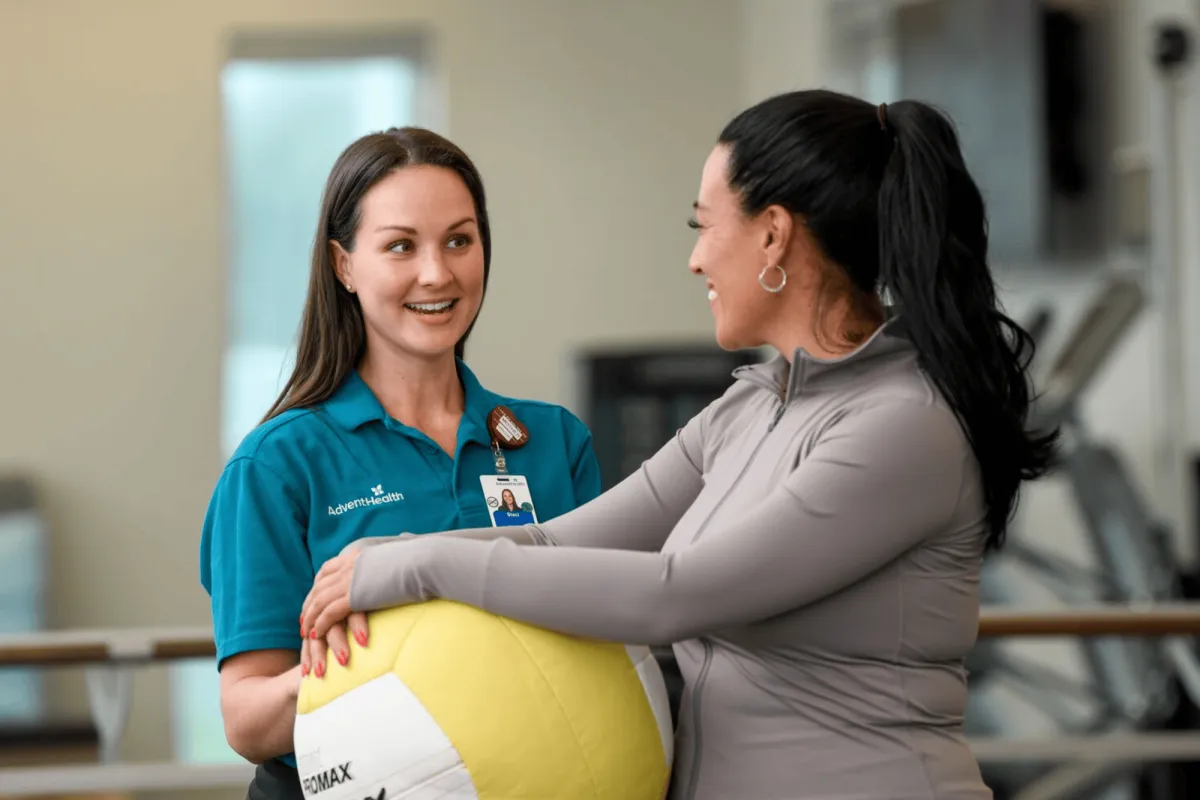 AdventHealth physician talking to patient holding yellow excercise ball