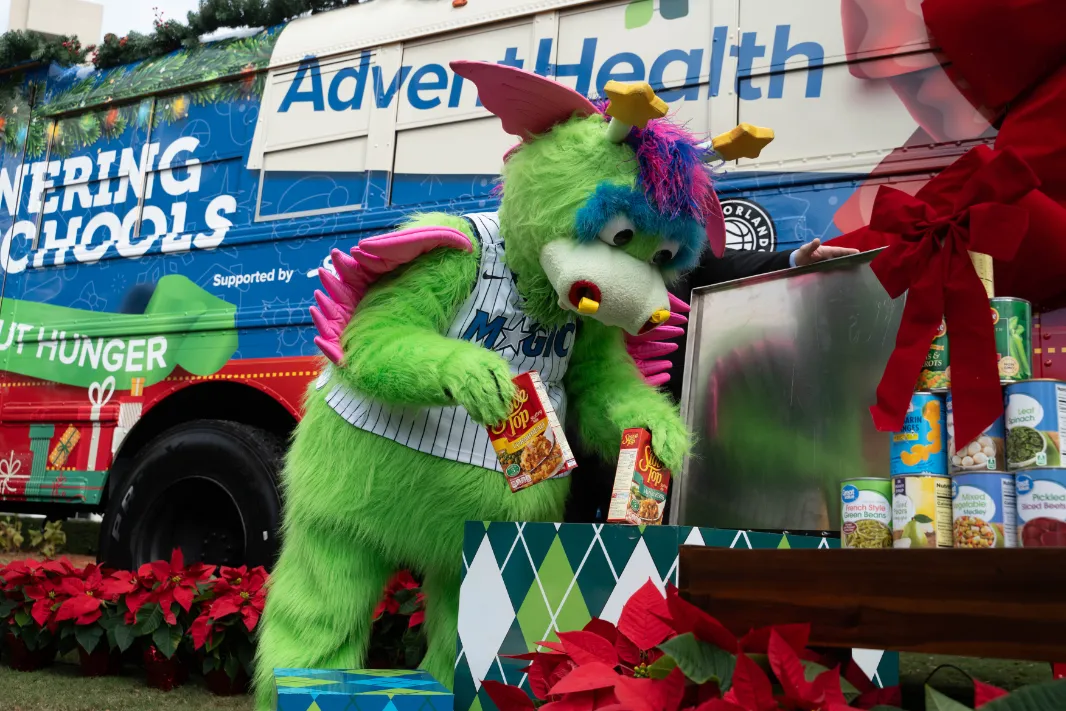 Orlando Magic mascot Stuff donates boxes of stuffing to the AdventHealth "Drive Out Hunger" Holiday Bus, which will be traveling around Orlando all December collecting non-perishables for local schools.