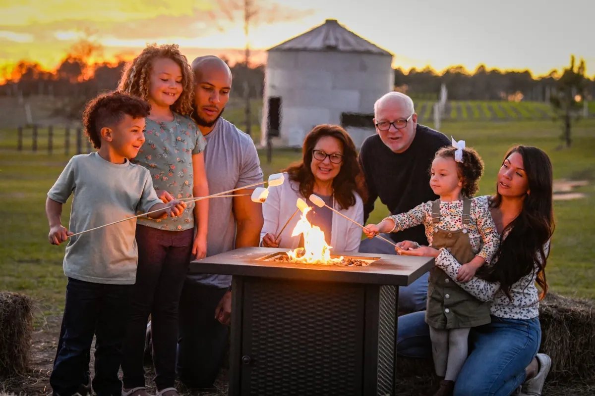 Seven family members gather around a fire to roast marshmallows.