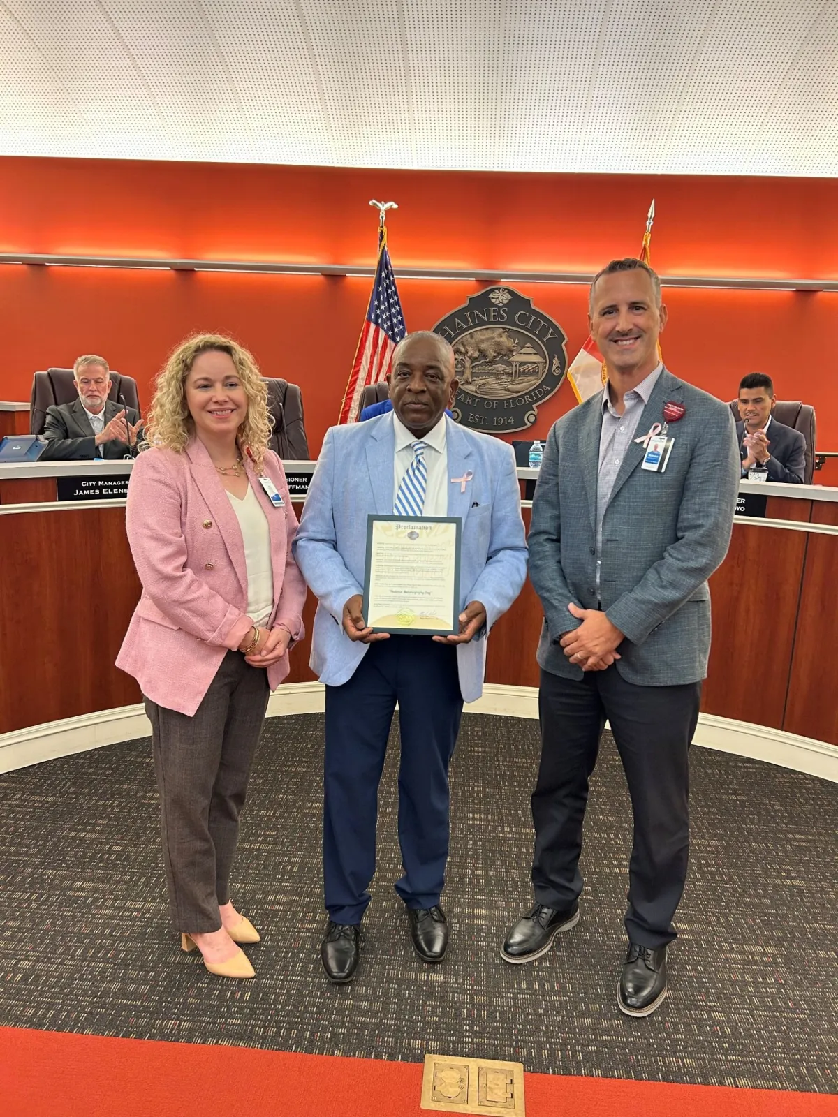 AdventHealth Heart of Florida Chief Operating Officer Julie Hess, Mayor Morris L. West, and Nick Plott, Government Advocacy Manager for AdventHealth West Florida Division with the National Mammography Day proclamation during a Haines City Commission meeting