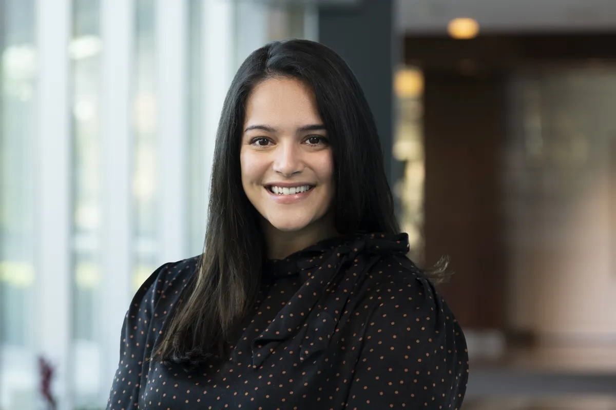 Jocelyn Shaw, a woman with dark hair wearing a black shirt, stands in front of a blurred office background 
