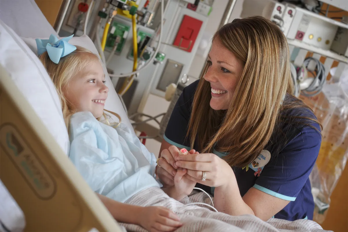 Smiling pediatric nurse with a little girl in a hospital bed