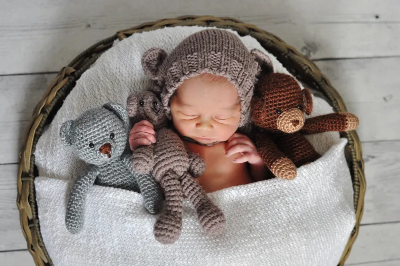 baby sleeping in basket with stuffed animals