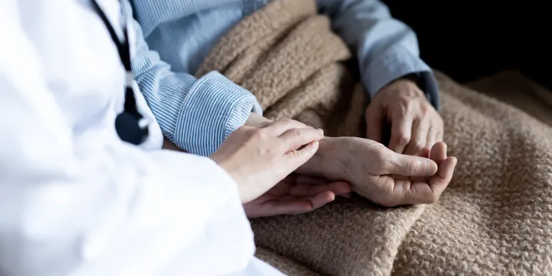 Close up of a physician's and hospice patient's hands.