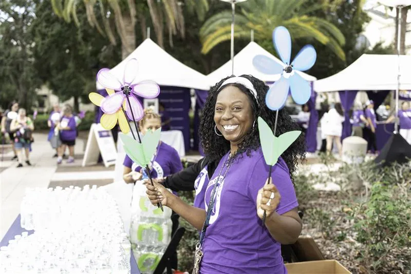 Smiling woman holding floral decoration at Walk to End Alzheimer's
